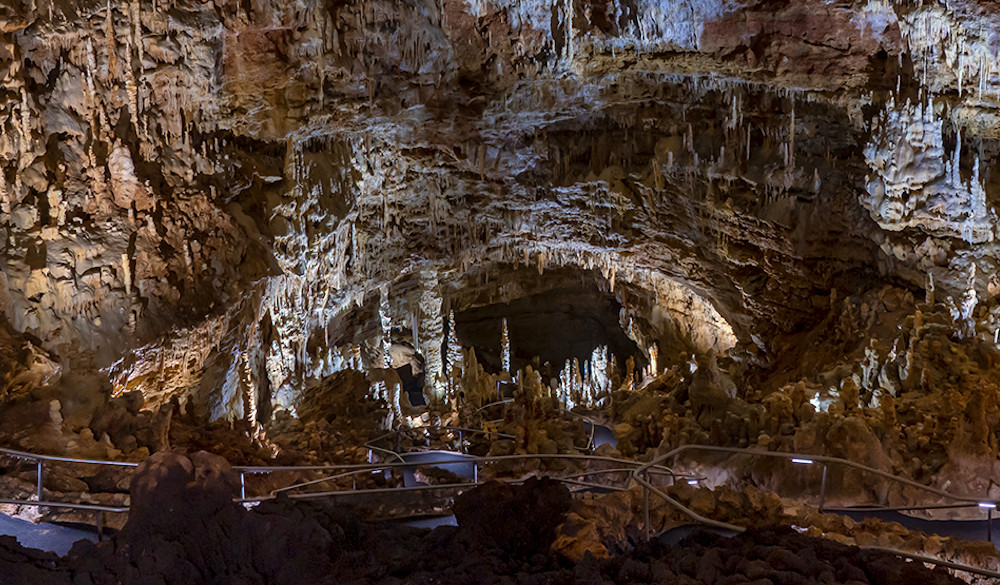 A view of expansive underground caverns with rock formations hanging from the walls.