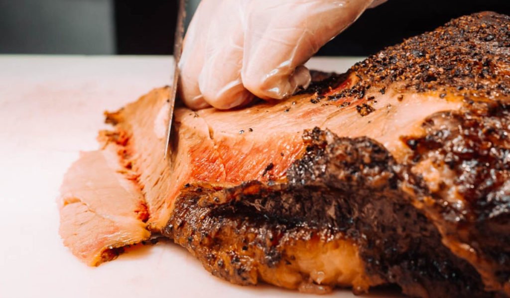 A person slices smoked brisket