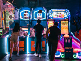 People play a basketball arcade game in a dimly lit arcade