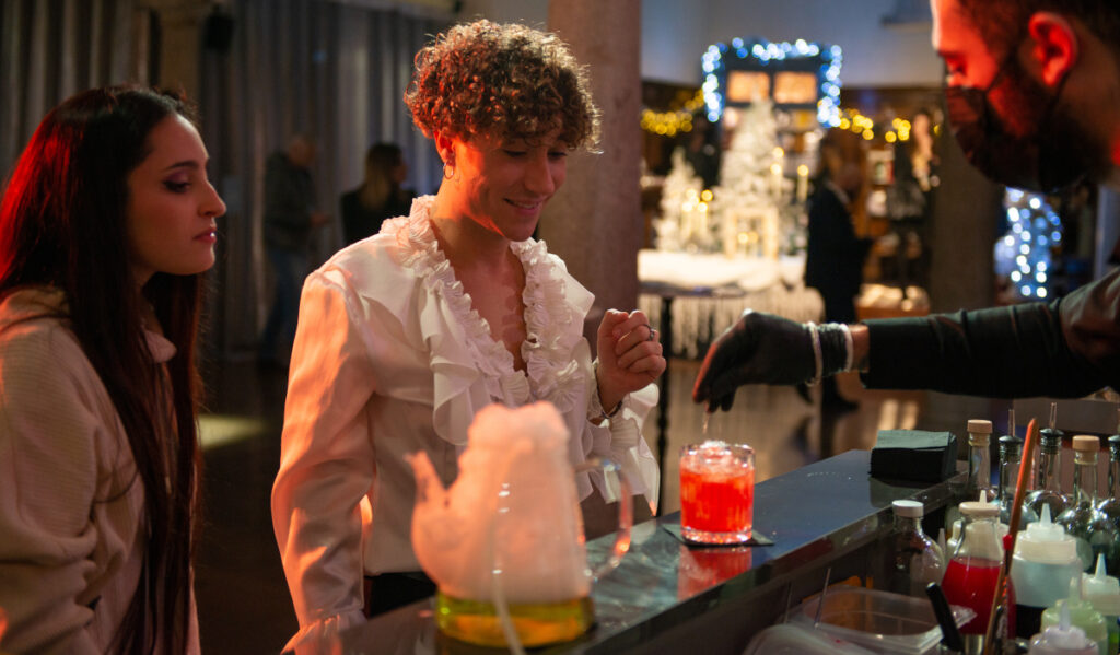 Party goers watch as a bartender makes a drink