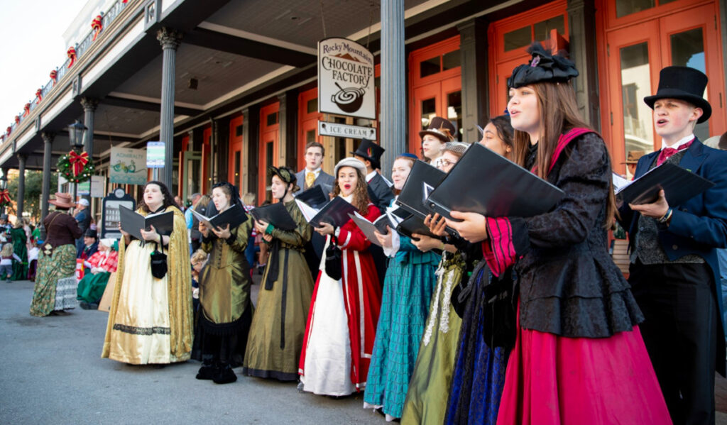 Carolers in Victorian dress sing on the street