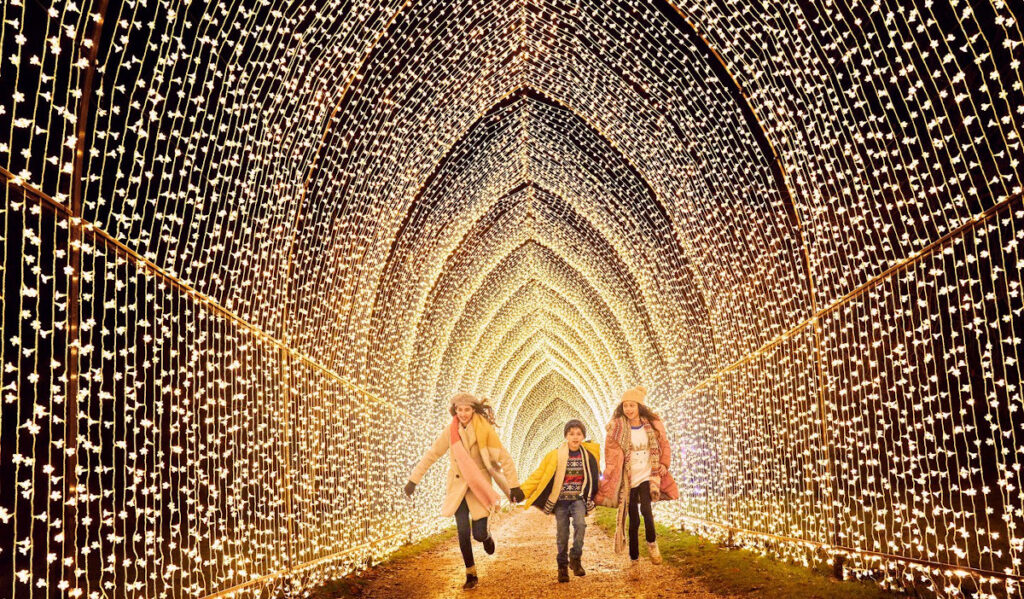 Kids run down a tunnel of Christmas lights