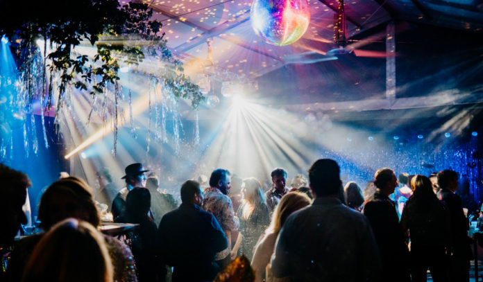 A crowd at a concert with a gleaming disco ball overhead