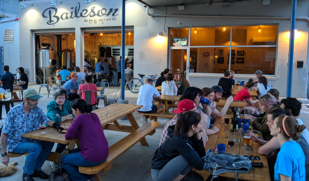 A patio filled with people outside of a brewery