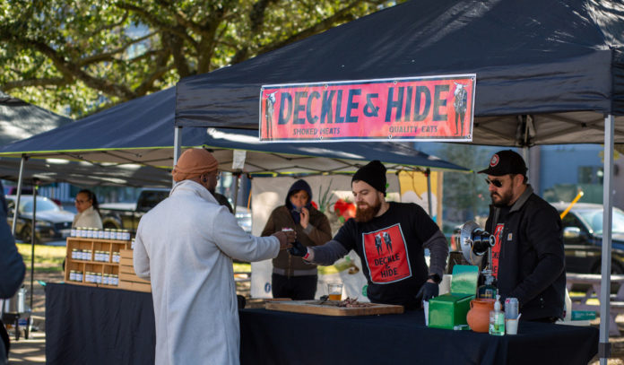 A chili vendor offers a sample to a customer