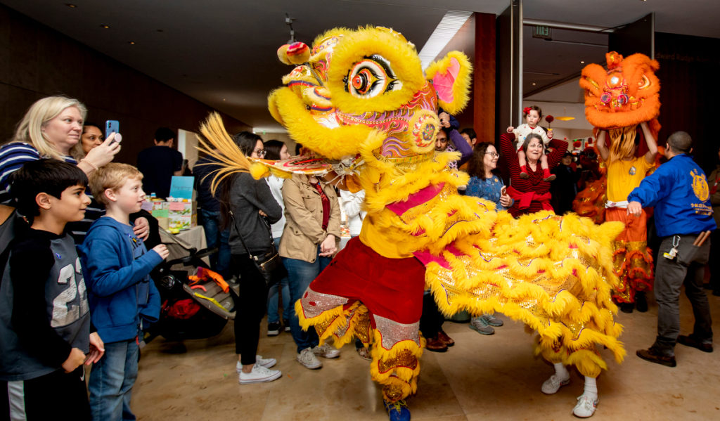 A traditional yellow lion dances among a crowd of families