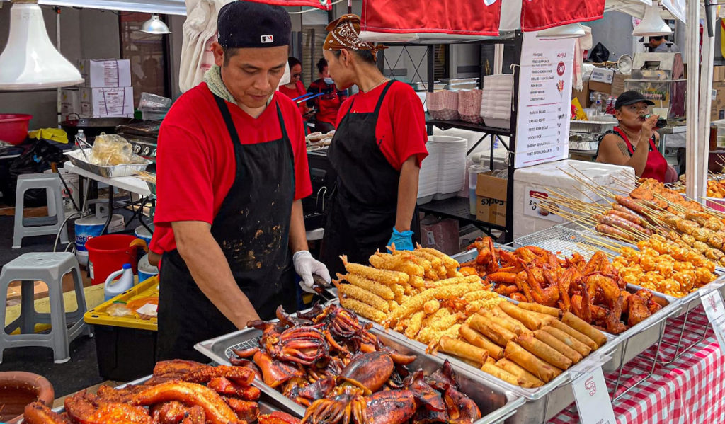 A food vendor serves fried street food delicacies at a festival