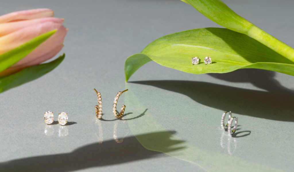 Four pairs of diamond earrings sit amid a leaf and flower