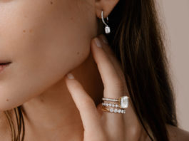 A closeup of diamond rings and a diamond earring near a woman's face