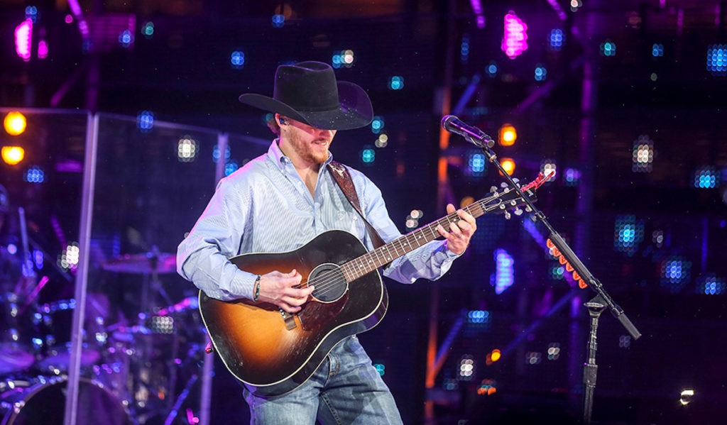 Country artist Cody Johnson plays an acoustic guitar on the Rodeo concert stage