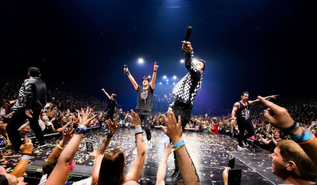 New Kids on the Block performs on stage while fans cheer around them