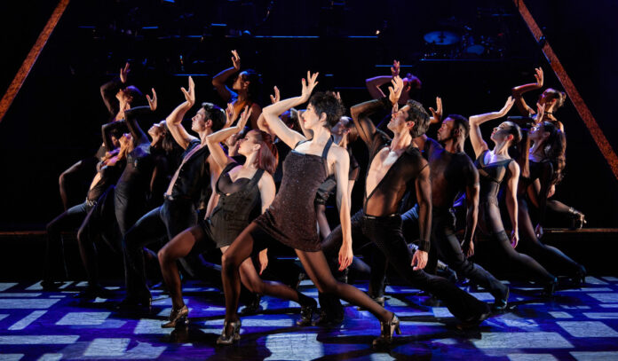 A troupe of performers dance in unison