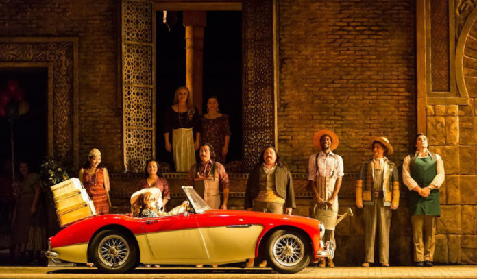 Houston Grand Opera performers stand in a line on stage as a car drives past