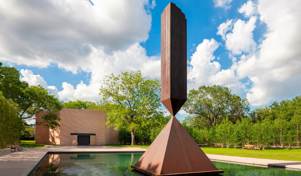 The "Broken Obelisk" sculpture sits foreground to the Rothko Chapel behind it