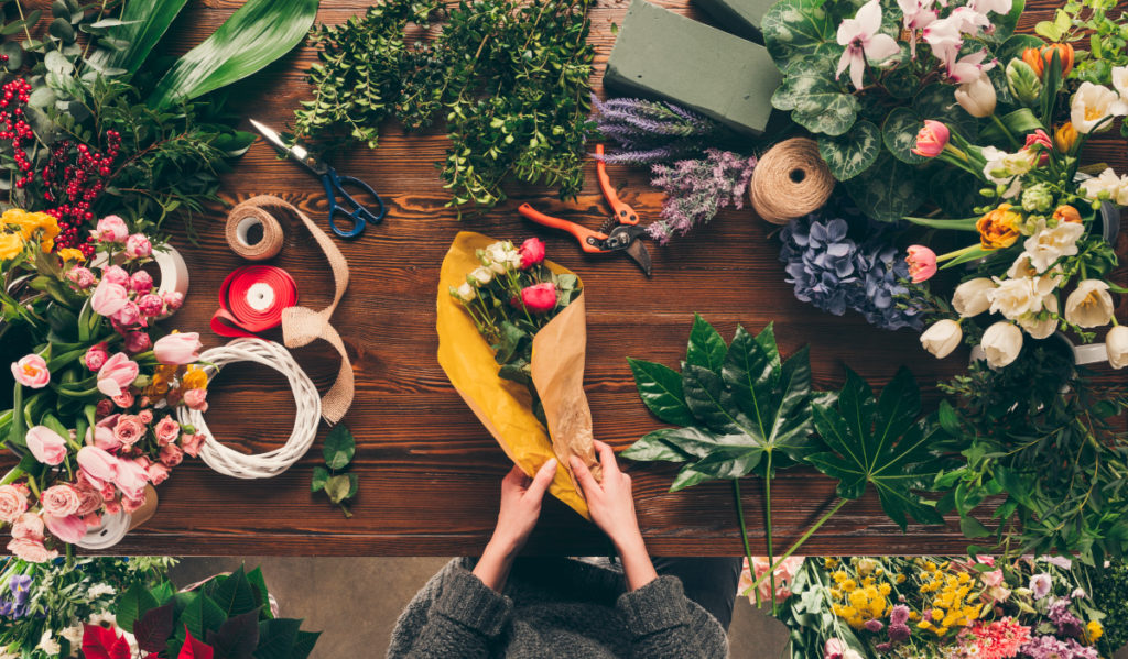 cropped image of florist wrapping bouquet in yellow pack paper