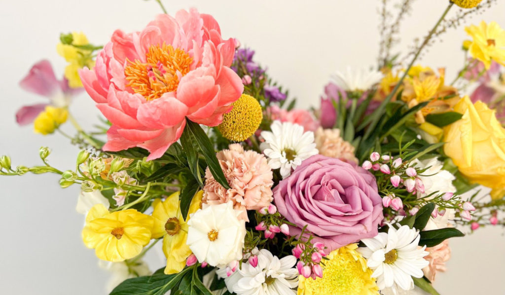 A flower arrangement with roses, daisies