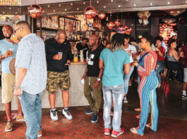 A crowd of people mingle around a bar