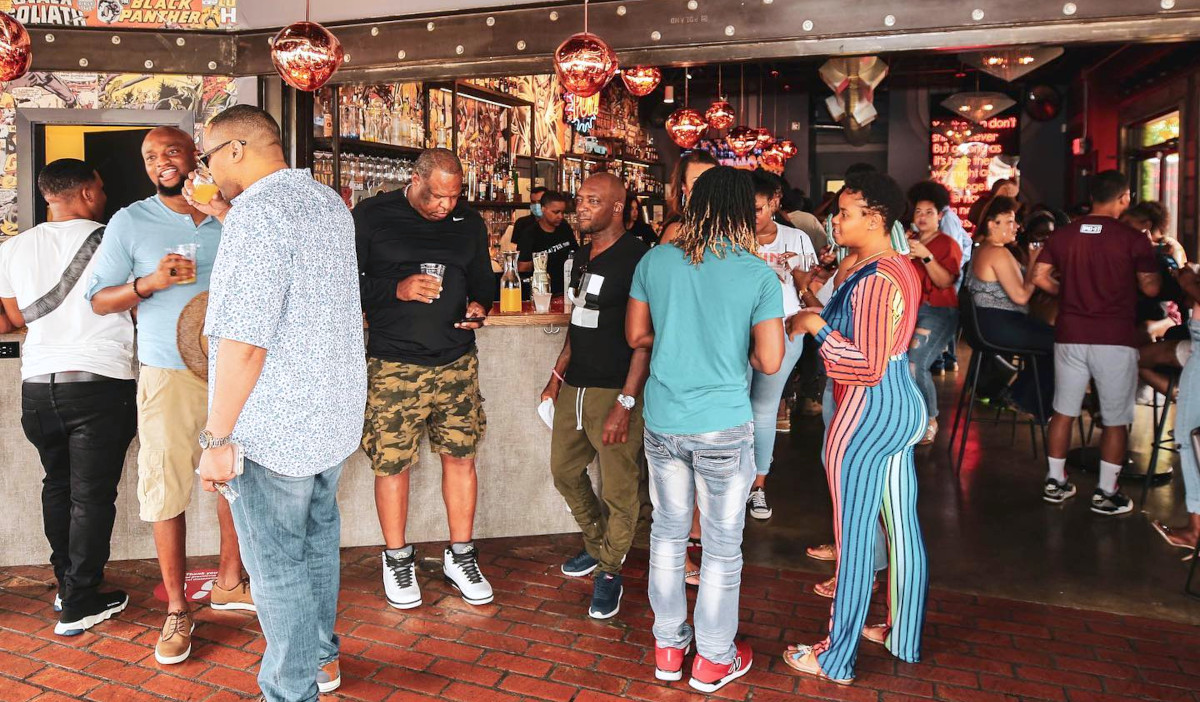 A crowd of people mingle around a bar