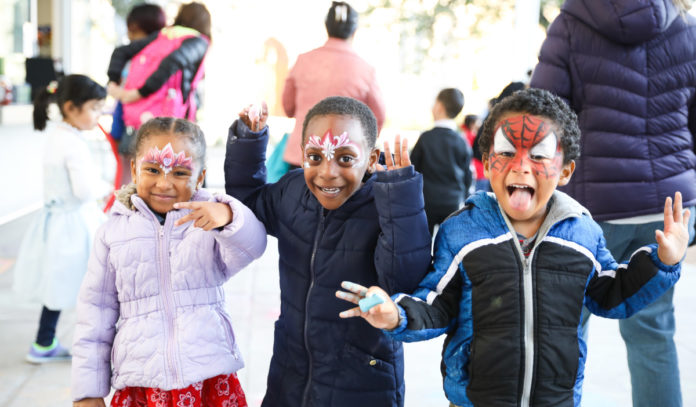 Three kids in face paint pose for the camera