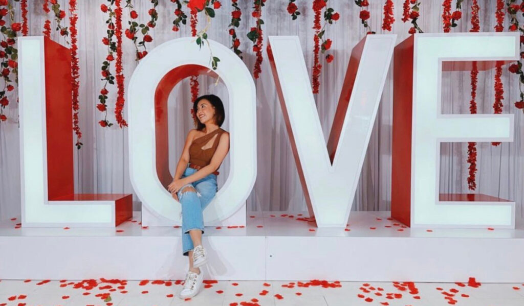 A woman poses next to giant L-O-V-E letters