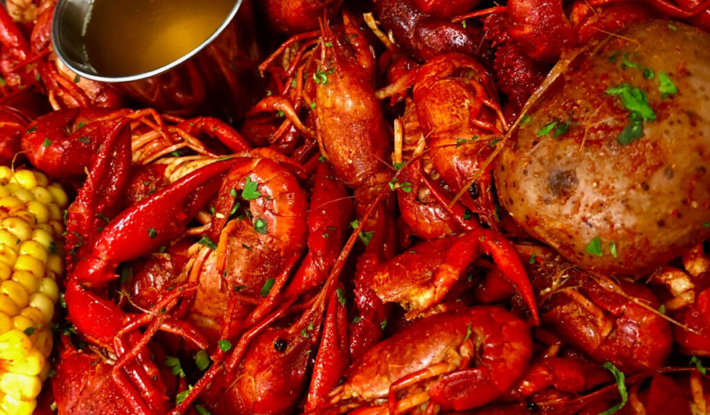 A close up of crawfish with butter garlic, potato and corn