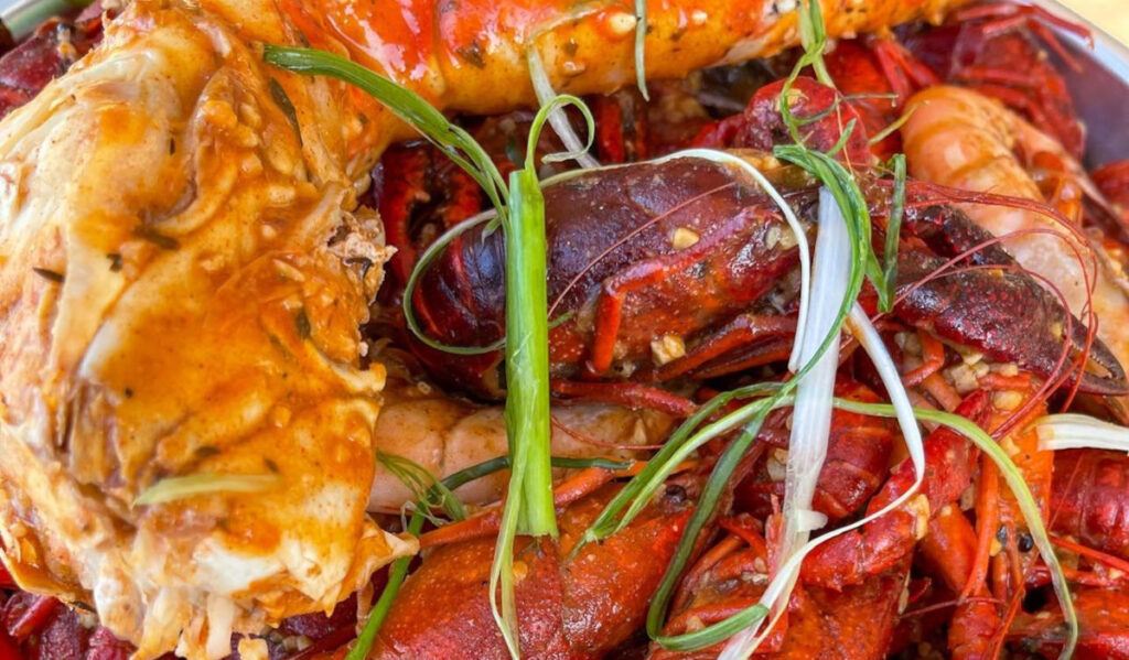 A close photo of crawfish and crab leg with lemon grass