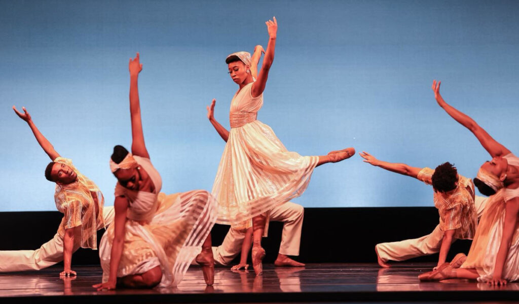 Dancers perform in unison on stage