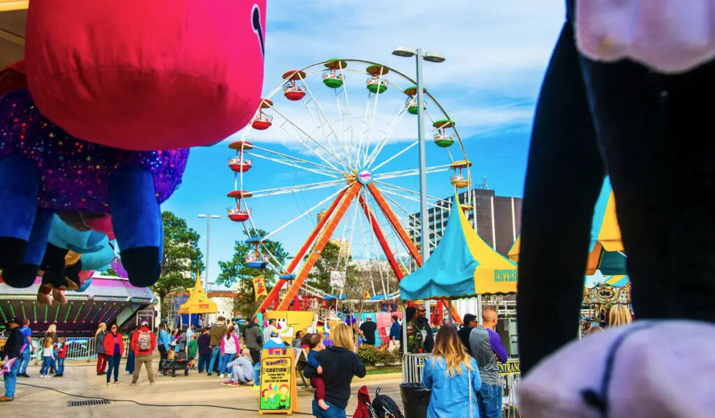 A carnival with Ferris Wheel and dangling prizes from game booths