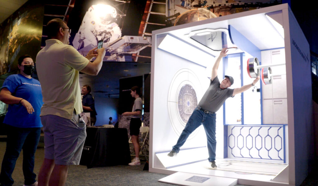 A visitor poses for a photo in a makeshift space station