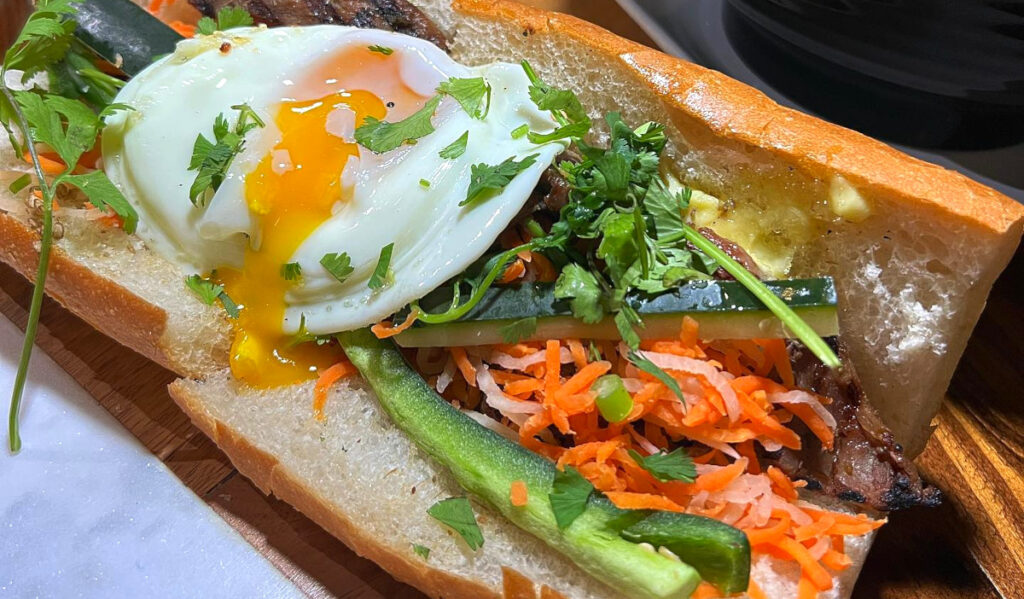 A banh mi sandwich with a runny egg on top
