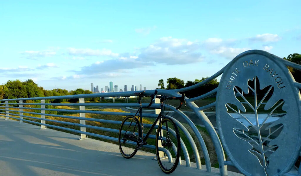 A bike leans against a bridge with the Downtown skyline in the far background