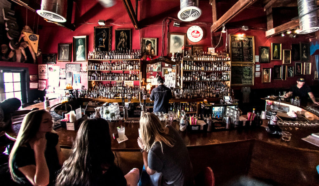 A wide shot of a bar with shelves of alcohol and decoration on the walls