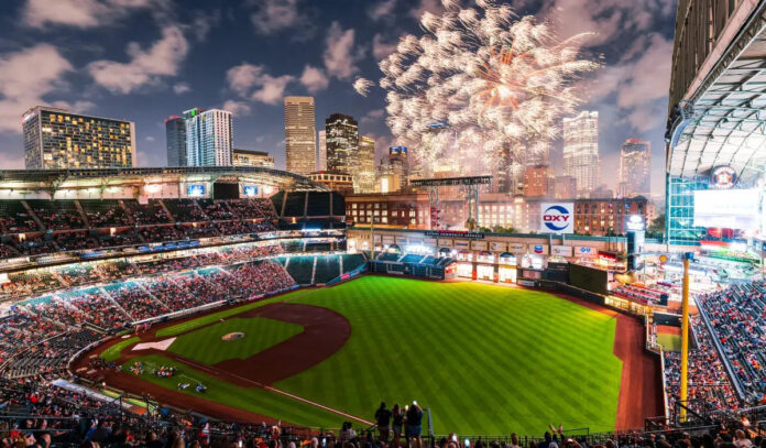 An overview of Minute Maid Park with the roof open, fireworks exploding, and the Downtown skyline in the background