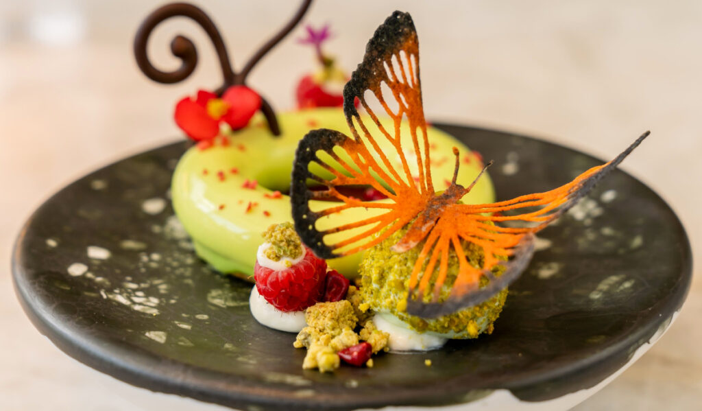 An ornate dessert plate with a butterfly garnish