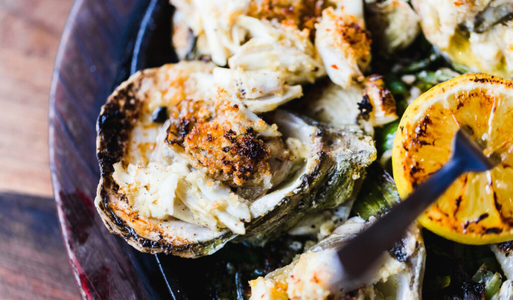 A close-up of roasted oysters on the half shell