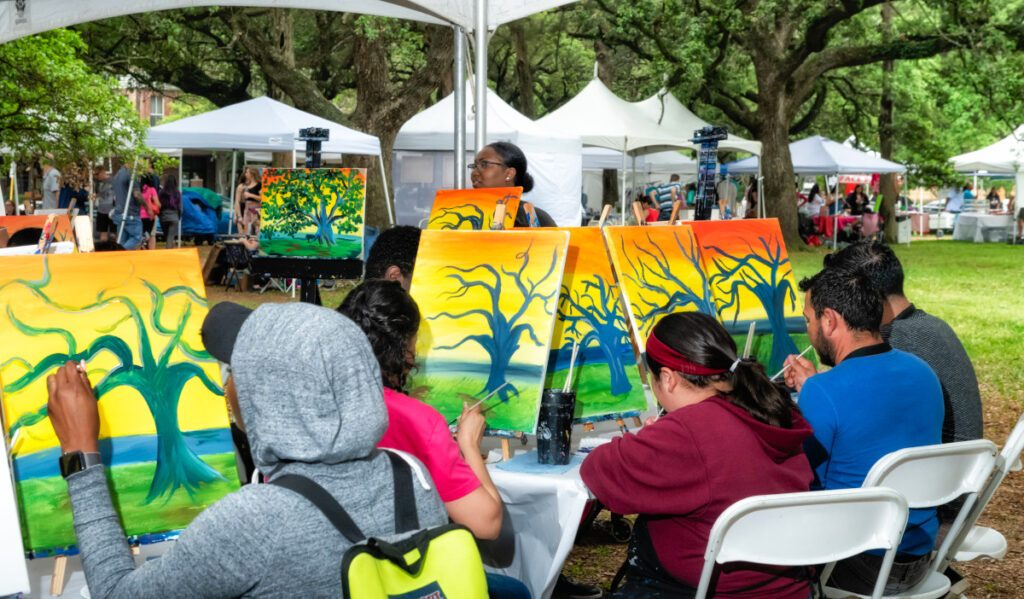 A class workshop of painters that are painting a tree at sunset