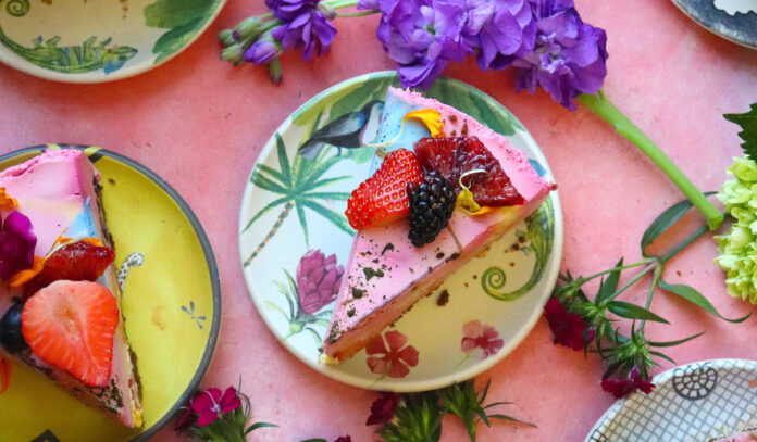 An overhead view of cake slices with fresh strawberries and flowers