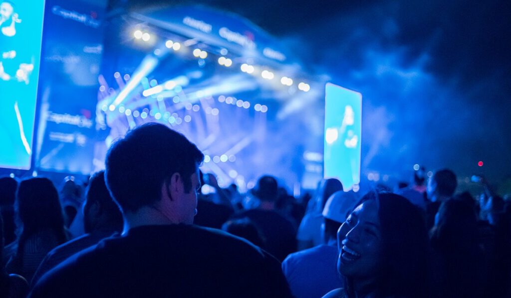 A close up of two fans with a blue-lit stage in the background