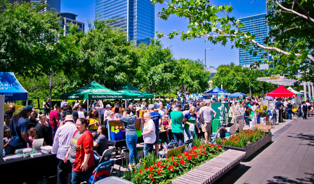 A bustling scene of people moving past informational booths and vendors