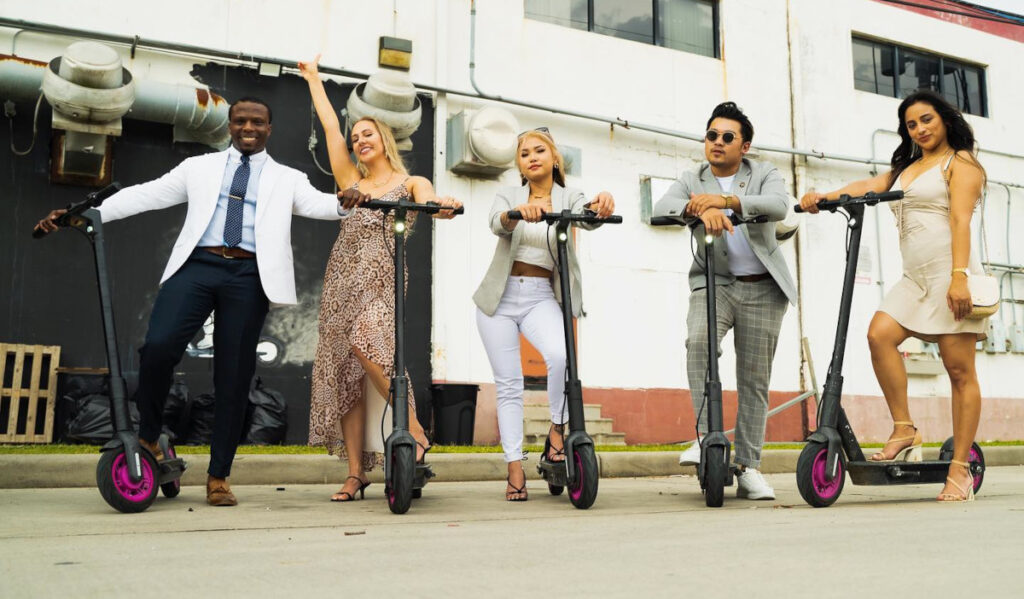 Five people in suits and nice dress pose on scooters