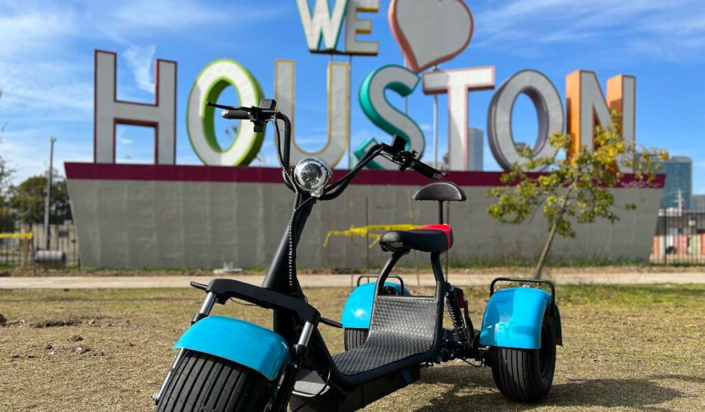 A three-wheel vehicle posed in front of a "We heart Houston" sign