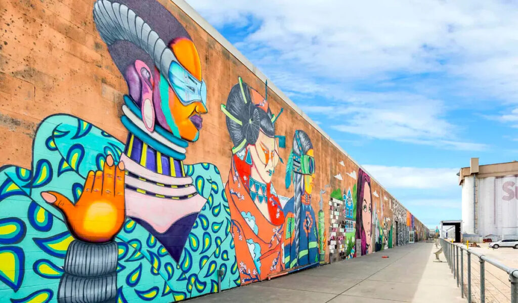 A mural of colorful characters in profile that extends far down a walkway