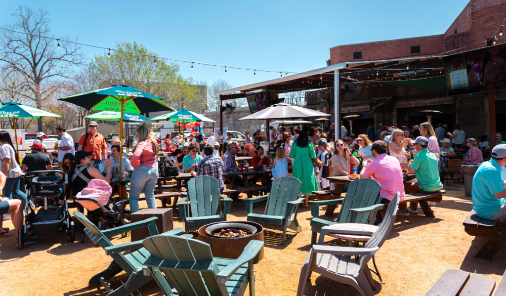 A bright, sunny patio with groups of people gathered and talking