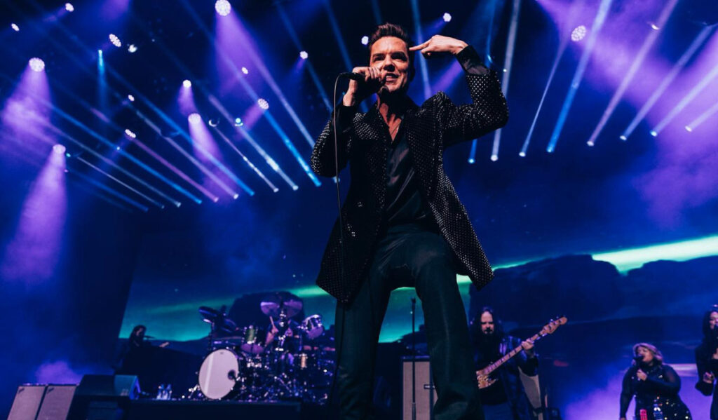 The Killers perform on stage with beams of light behind them