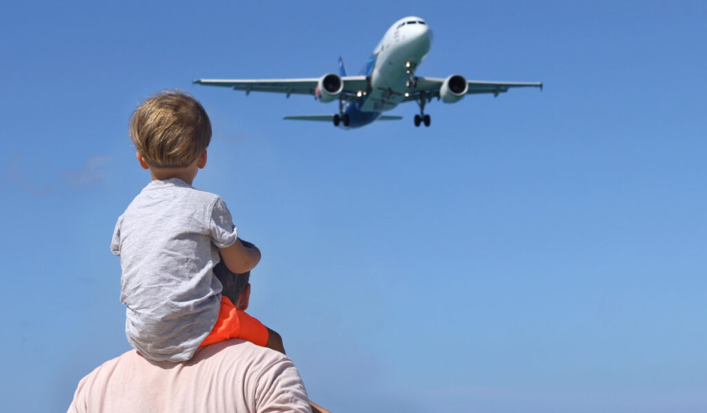 A father and son watch a low-flying plane overhead