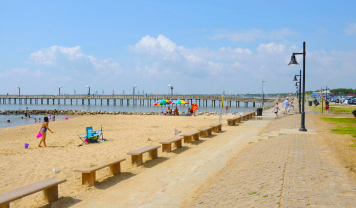 A beach scene with a child playing and people sitting under an umbrella