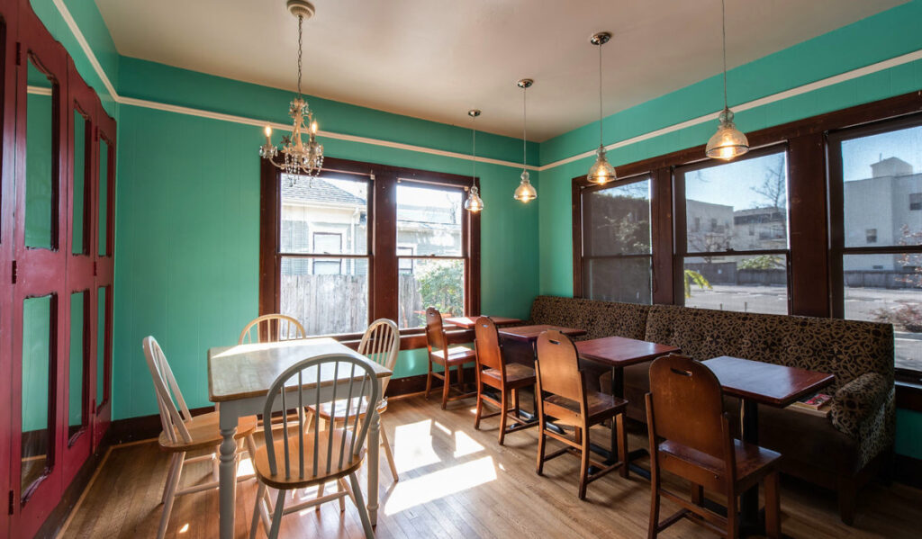 A light-filled interior room with a table and a bench of seating