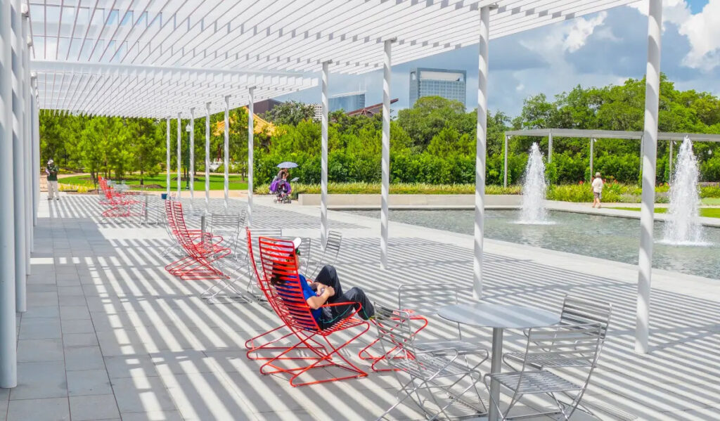 An outdoor scene of a person in a reclining chair next to fountains in a park