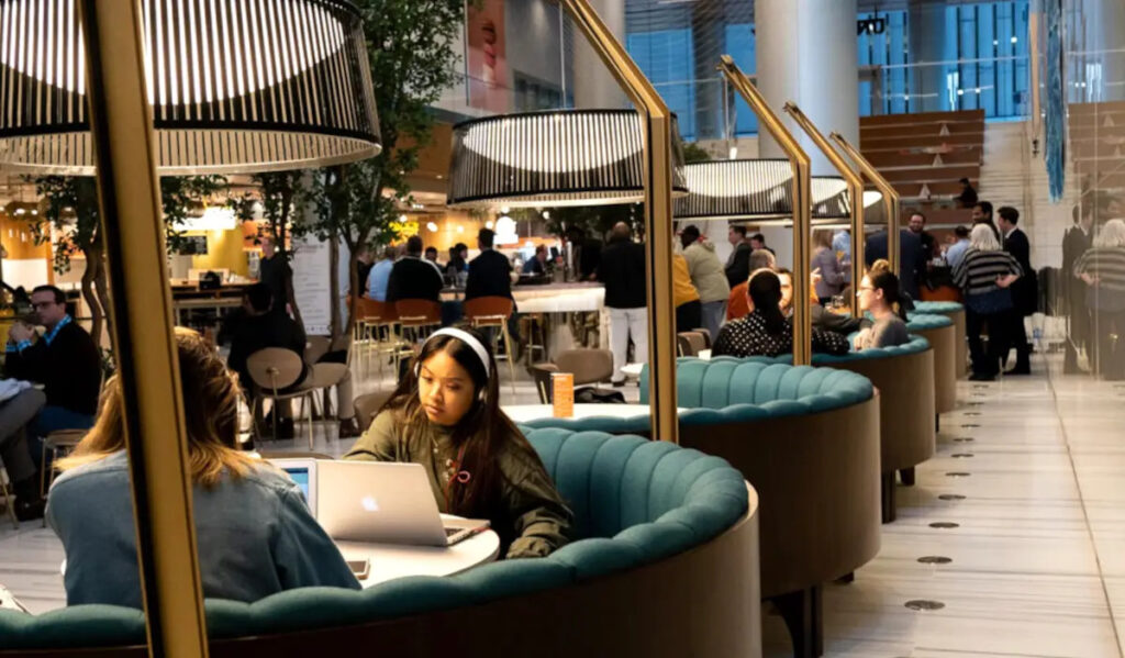 Round booths line a wall with people using laptops and talking with each other