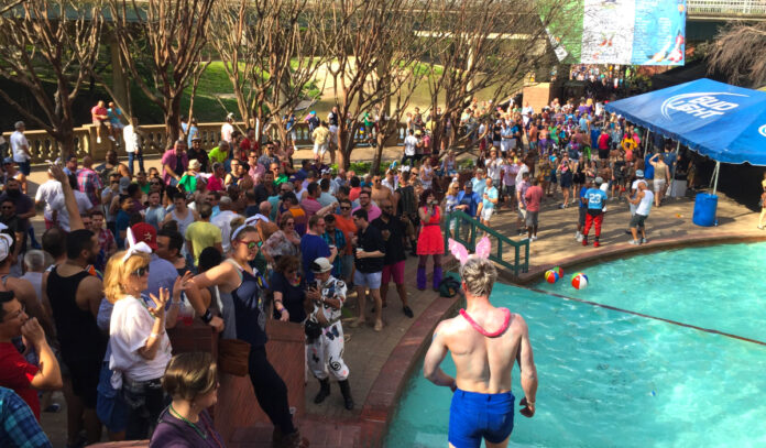 Crowds of people stand alongside a pool of water